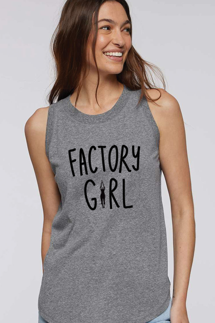 A woman wearing a grey tank top with the text "FACTORY GIRL" printed on it, smiling and looking to the side.
